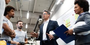 Factory manager holding a meeting and talking to his employees about project plans.